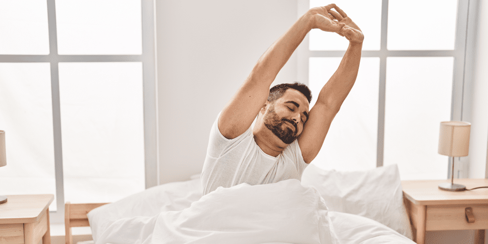 man stretching his arms in bed