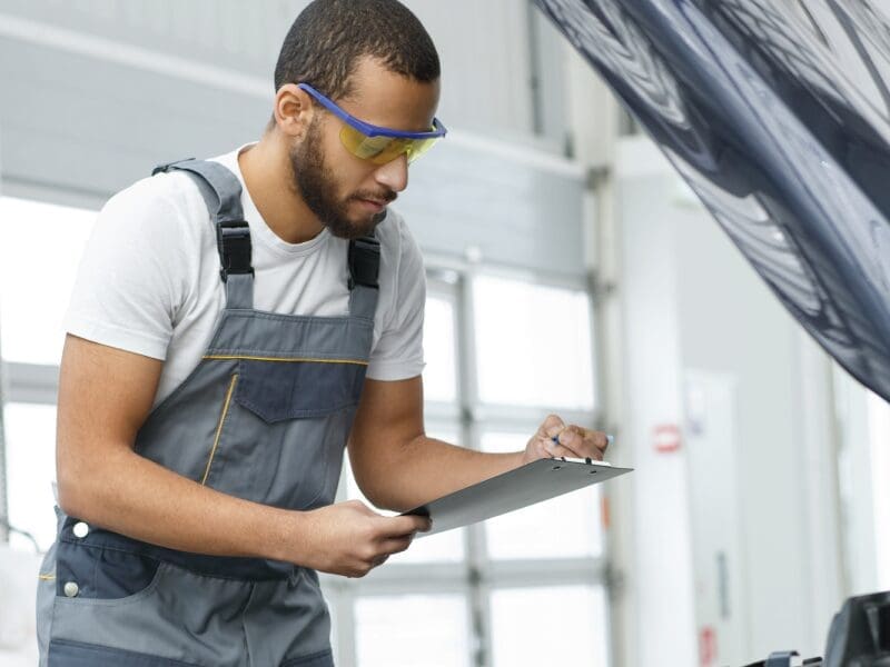 Automotive worker looking at a checklist during a tune-up